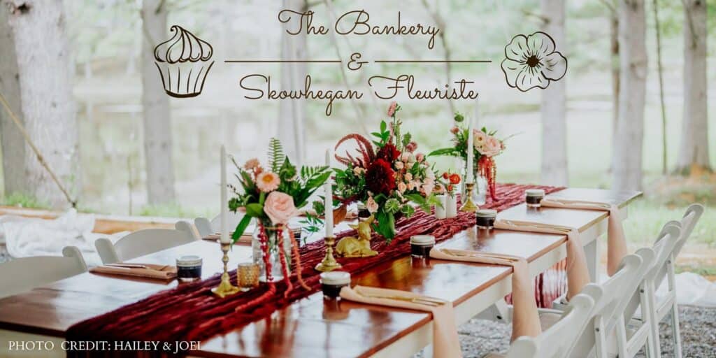 Outdoor dining table with floral centerpieces on wooden surfaces under trees. A banner reads "The Bankery and Skowhegan Fleuriste." Photo by Hailey and Joel.